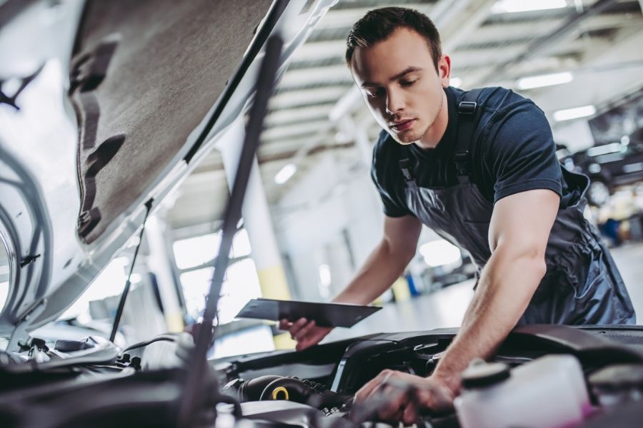 Technician looking under hood of car