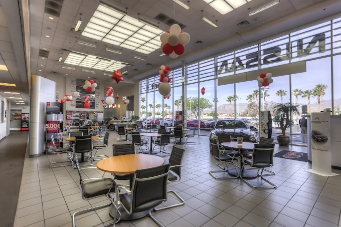 Nissan car dealership interior with tables and balloons, bright and airy.