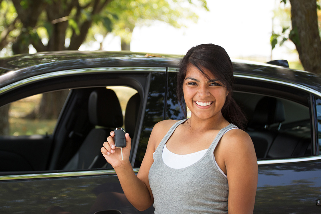 Car salespeople of different genders and nationalities standing with folded arms looking at the camera.