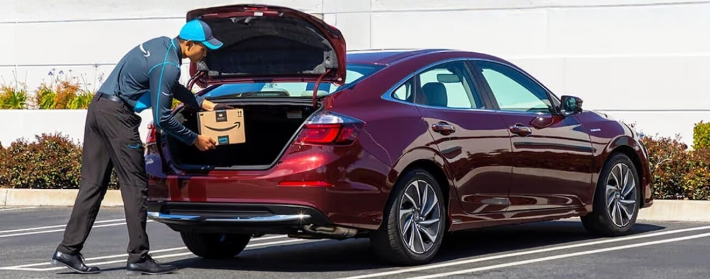Delivery driver is leaving packages in the trunk of a red 2021 Honda Insight Touring