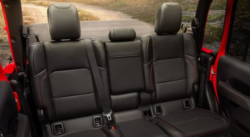 A close-up shows the rear black leather seats in a red 2024 Jeep Gladiator.