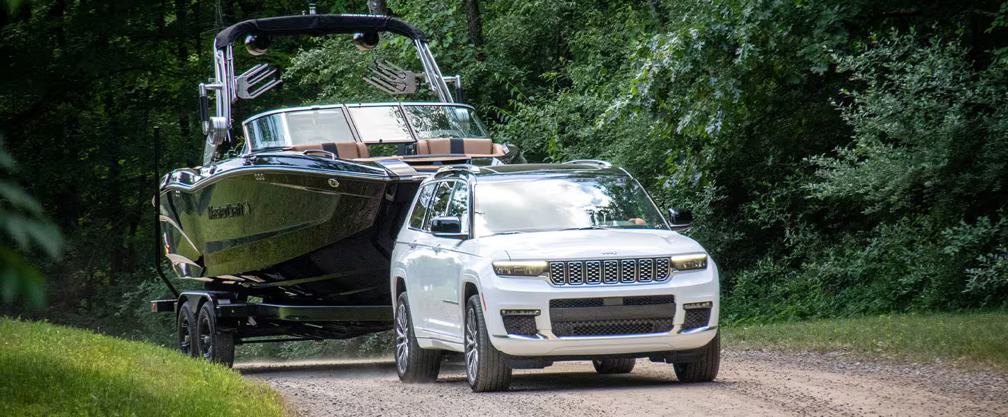 A white suv pulling a boat on the road.