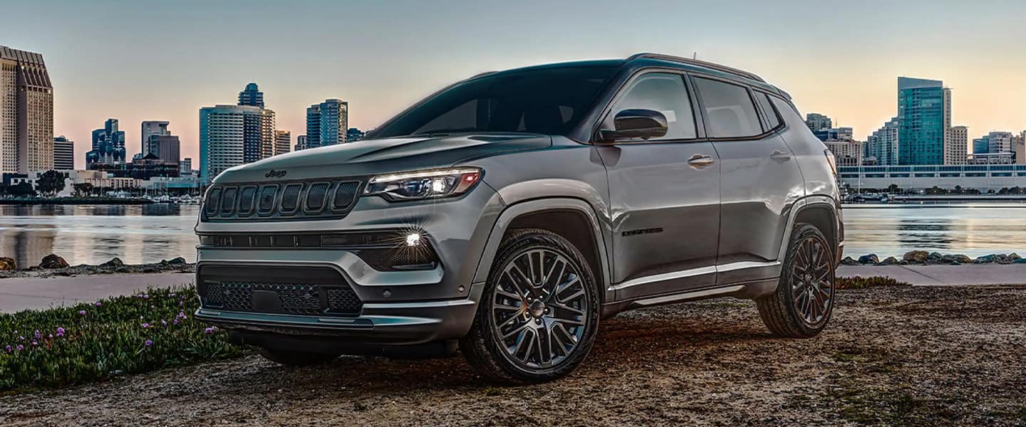 A gray jeep sitting parked in front of some water.