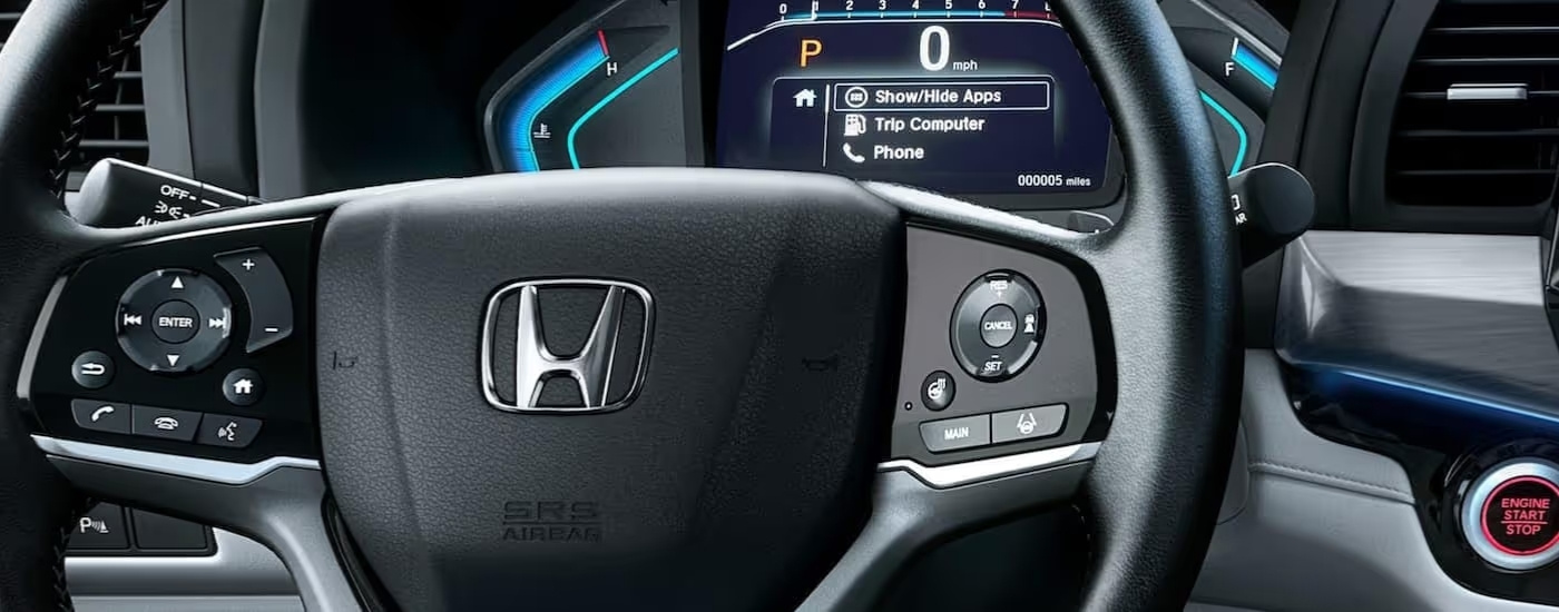 Close up shows the steering wheel and gauge cluster in a 2022 Honda Odyssey