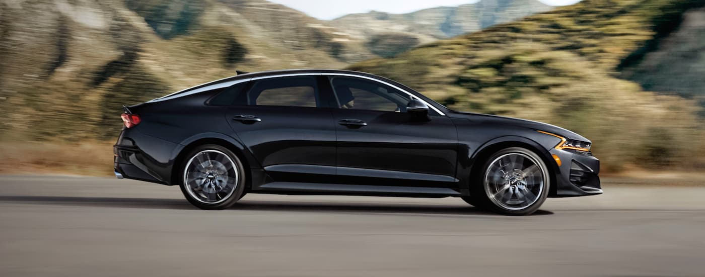 Black 2021 Kia K5 driving on an open road