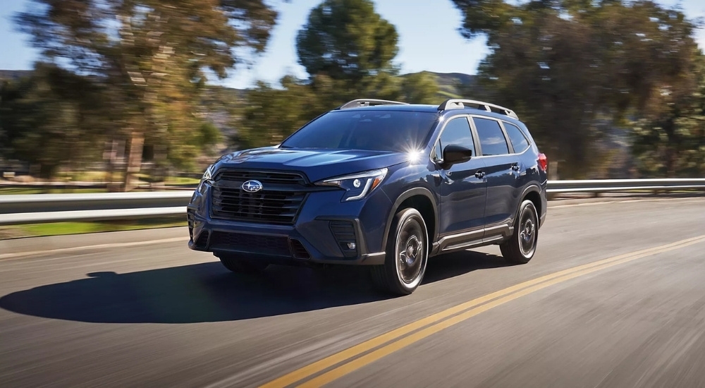 A dark blue 2025 Subaru Ascent Onyx Edition driving on sunny day.