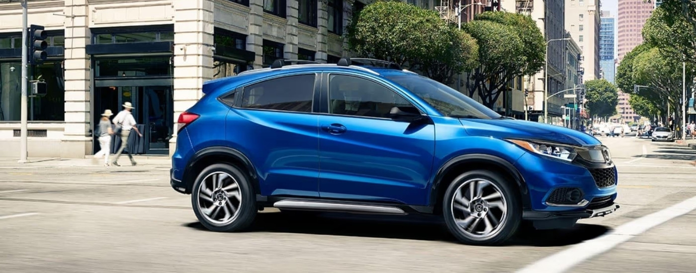 Blue 2020 Honda HR-V Sport is driving on a city street near Rochester, NY