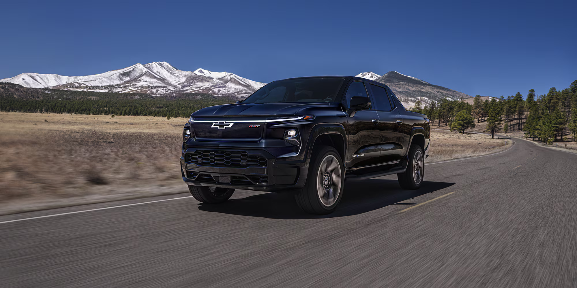 A black truck driving on the road.