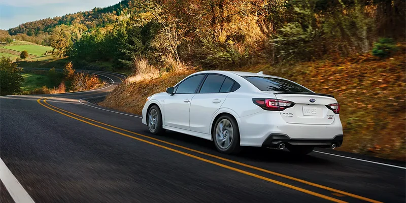 White 2023 Subaru Legacy sedan driving on a coastal highway