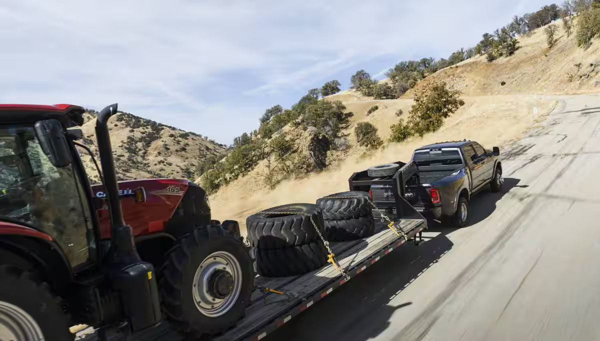 A black truck pulling a trailer with equipment on it.