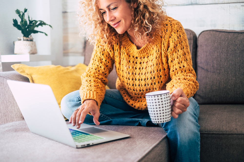 woman smiles while holding coffee and using the Accelerate Your Deal tool online, while shopping for cars