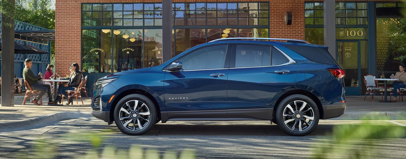 A blue 2023 Chevy Equinox Premier is parked on the side of a city street.