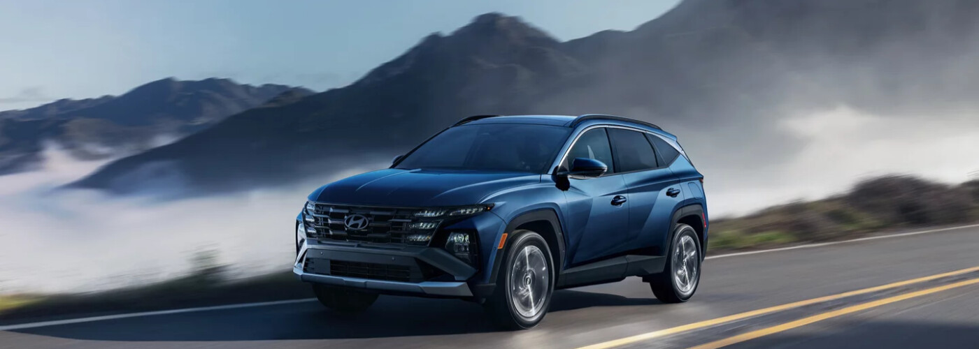 Blue Hyundai Tucson driving on a mountain road above the clouds