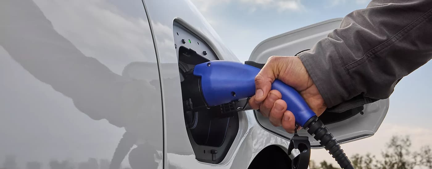 Hand plugging an EV charger into a white 2026 Subaru Solterra.