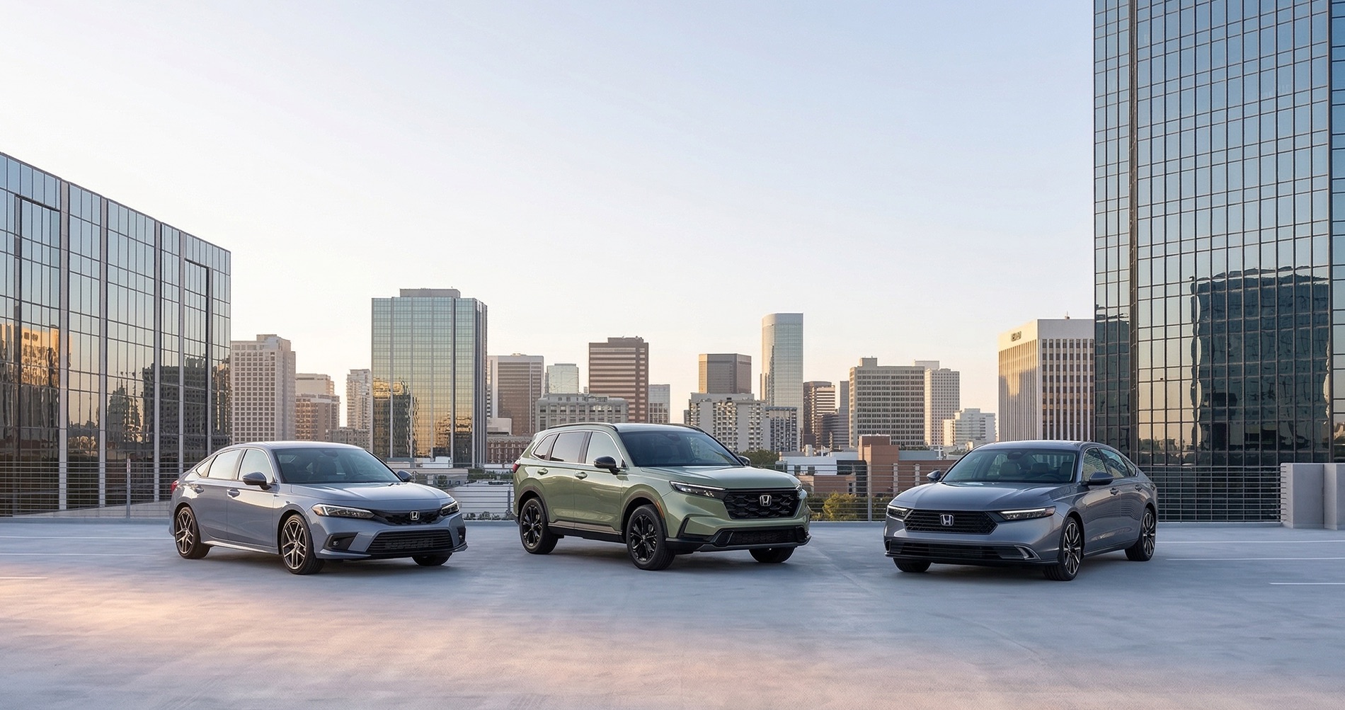Honda Civic, CR-V, and Accord parked on a rooftop parking garage with city skyline representing fuel efficient Honda vehicles
