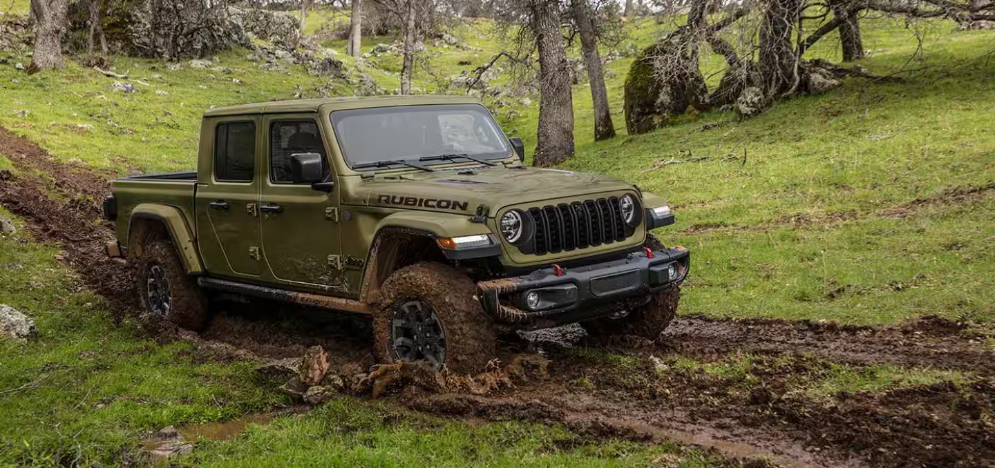 A green jeep driving through the mud.