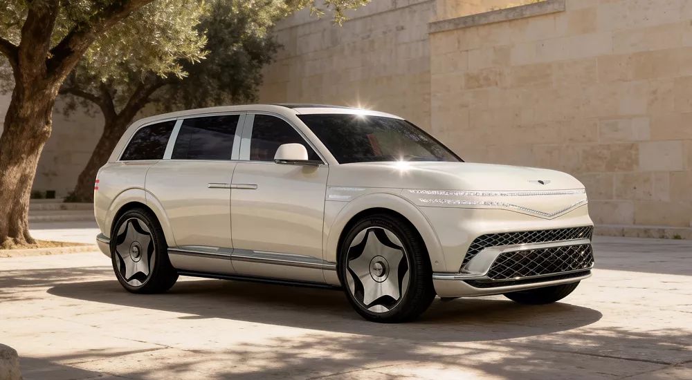 A white 2027 Genesis GV90 Neolun parked by trees.
