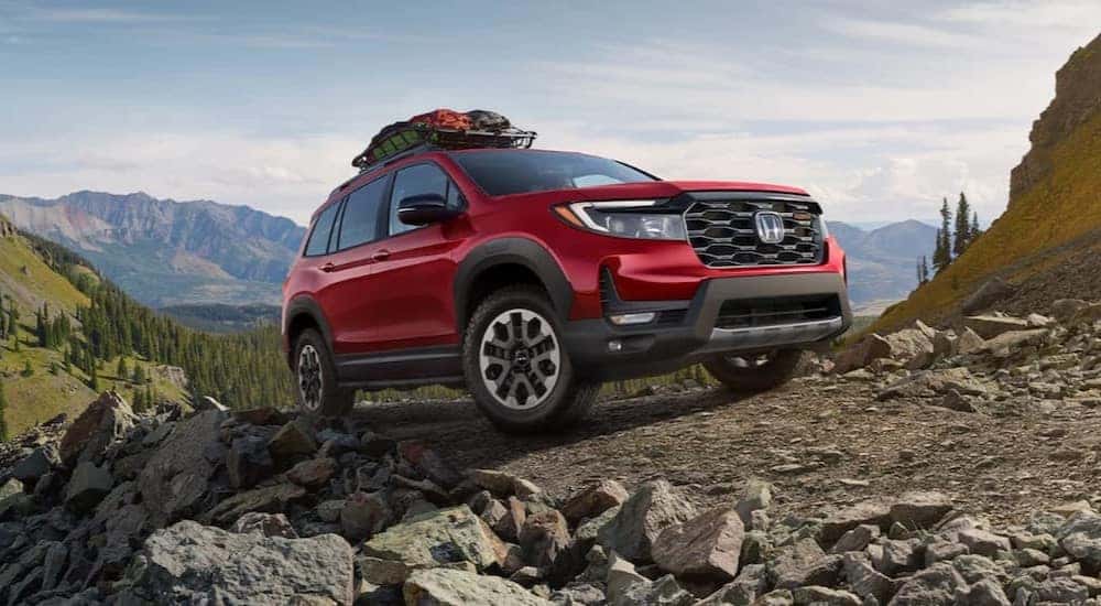 Red 2024 Honda Passport TrailSport for sale parked on a rocky path.