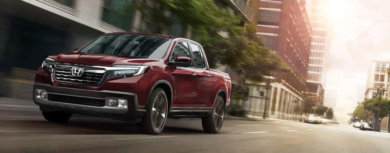 A red 2020 Honda Ridgeline RTL-E is shown driving on a city street