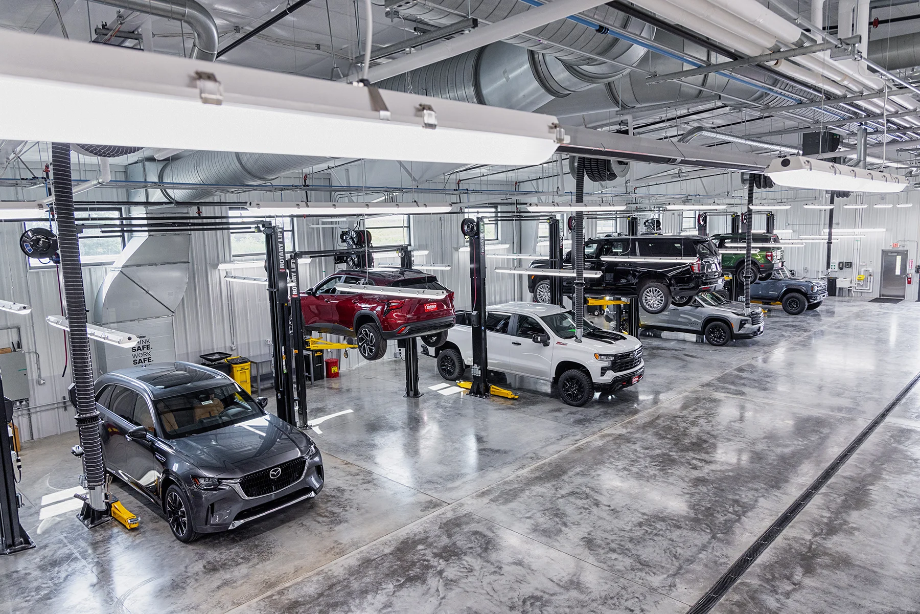 A very clean and bright automotive service and repair facility in Fond du Lac, WI with a variety of shiny vehicles on and off car lifts.