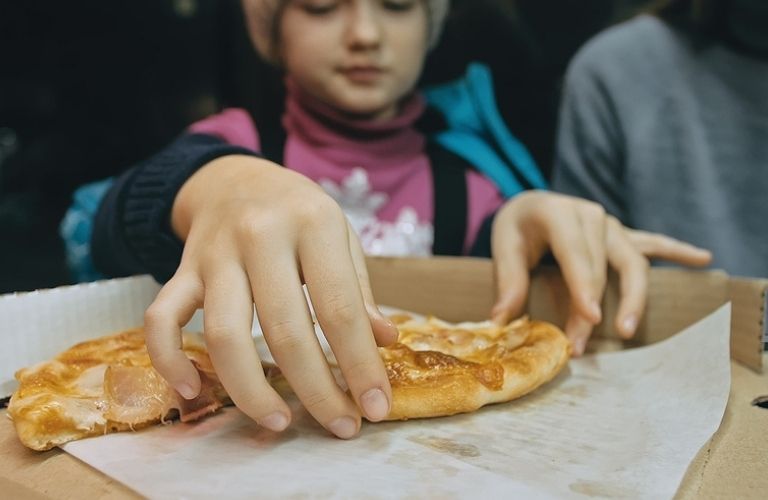 A child picking a slice of pizza.