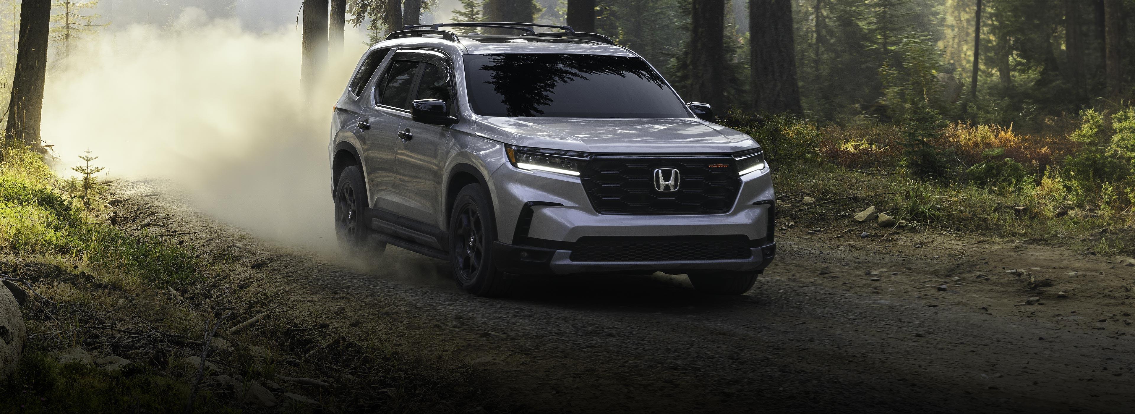Grey 2025 Honda Pilot Trailsport driving on a dirt road