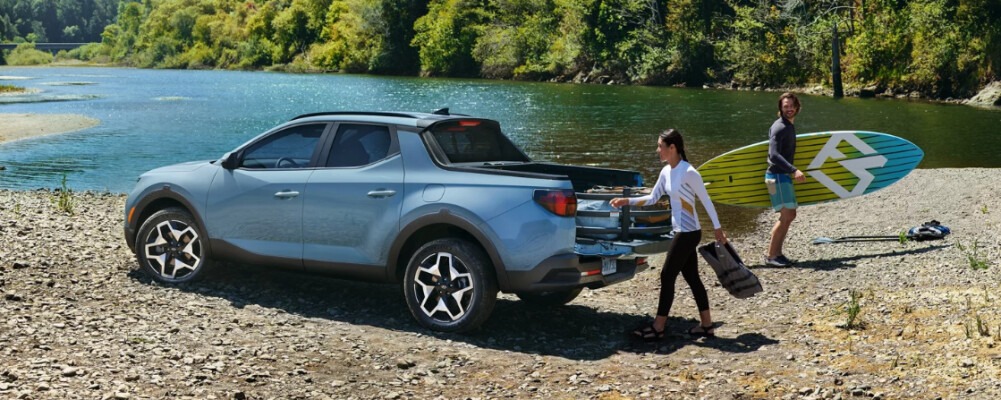 Couple unloading paddleboards from a Hyundai Santa Cruz by a river