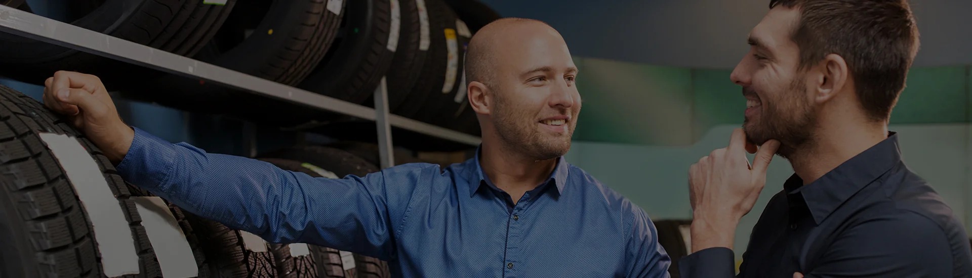 Dalton Subaru service advisor greeting a customer in front of a tire display