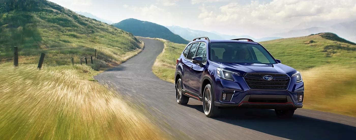 Blue 2023 Subaru Forester is shown driving on a road