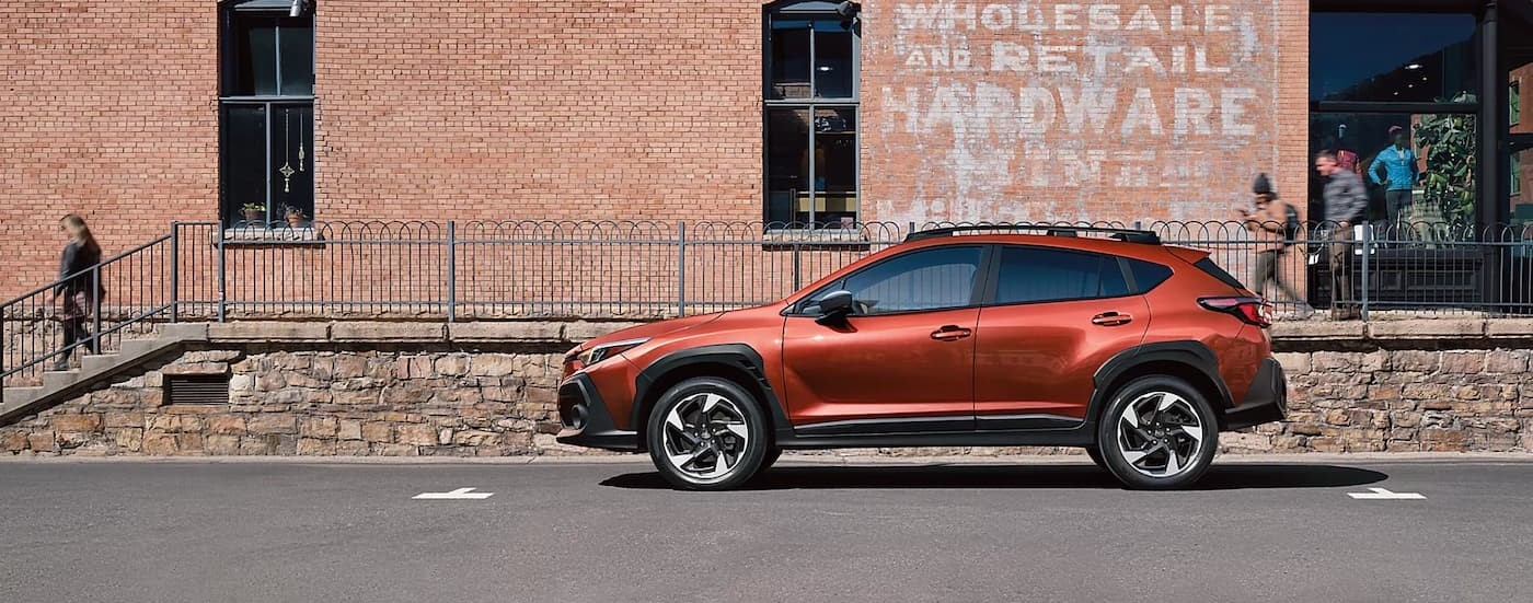 An orange 2024 Subaru Crosstrek is shown parked near a Subaru dealer near Hudson.