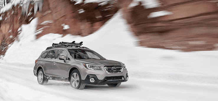 Silver Subaru Outback driving through snow