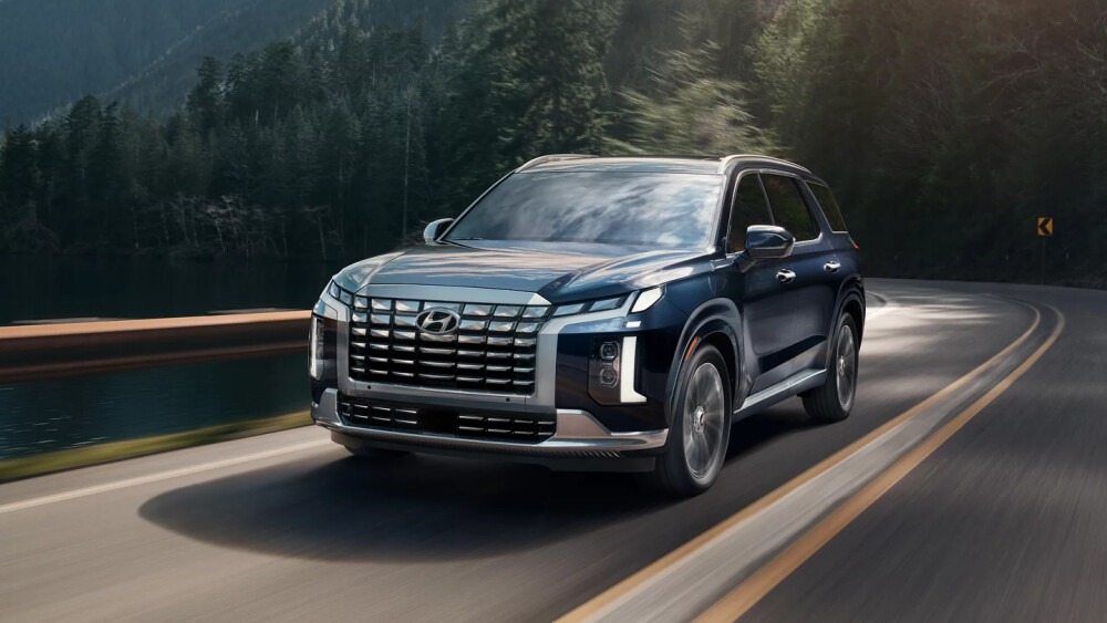Gray 2025 Hyundai Palisade driving on a winding forest road