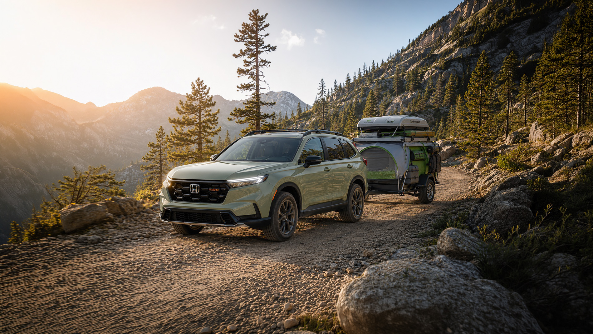 2026 Honda CR-V TrailSport Hybrid shown with a compact lightweight camping trailer in a mountain setting