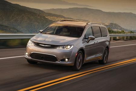 Silver Chrysler Pacifica minivan driving on a mountain highway at dusk