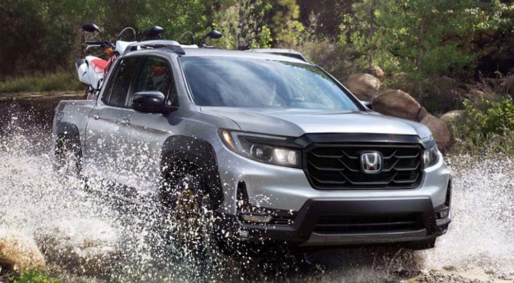 A grey 2023 Honda Ridgeline Sport HPD is shown driving through a river.