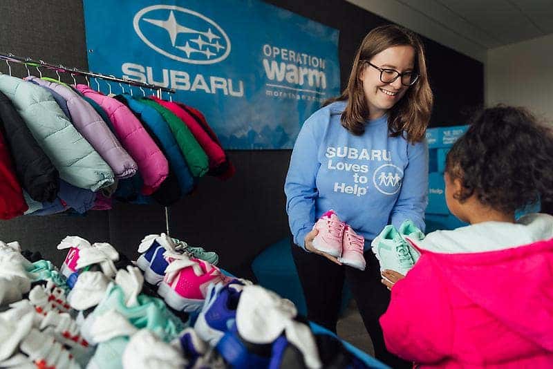 Volunteer handing out coats and shoes at an Operation Warm event