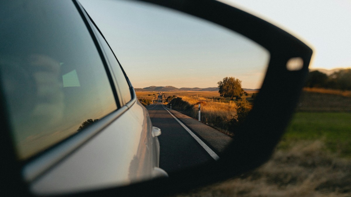 View of a Summer Road Stretching Backwards in the Side Mirror of a Car