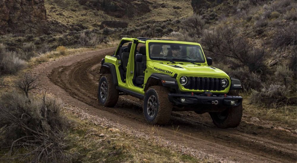 A green 2024 Jeep Wrangler Unlimited is shown rounding a corner after leaving a Jeep dealer.