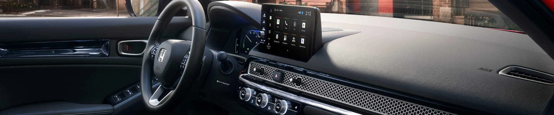 Honda vehicle interior featuring a steering wheel, digital instrument cluster, touchscreen display, and climate controls.