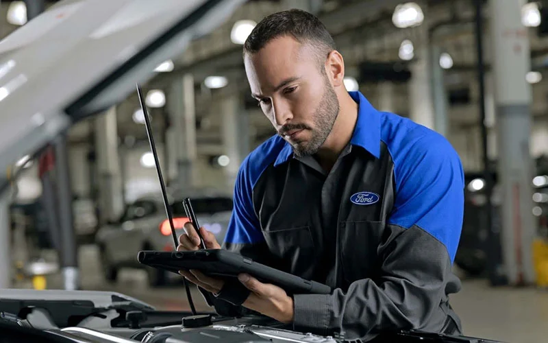 image of ford service employee taking notes on ipad over vehicle