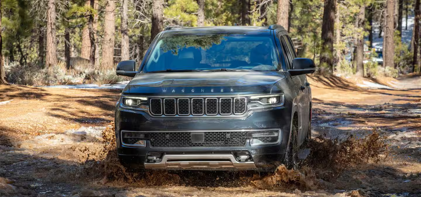 A black wagoneer driving through the mud.