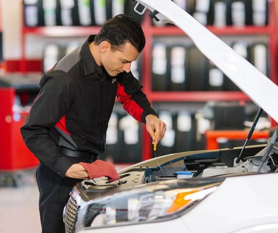 Kia technician checking the oil level on a vehicle during an oil change service