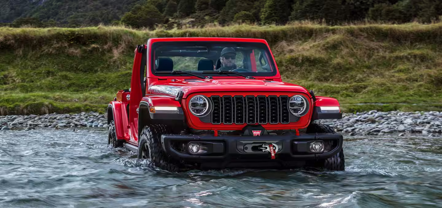 a red jeep sitting in water.