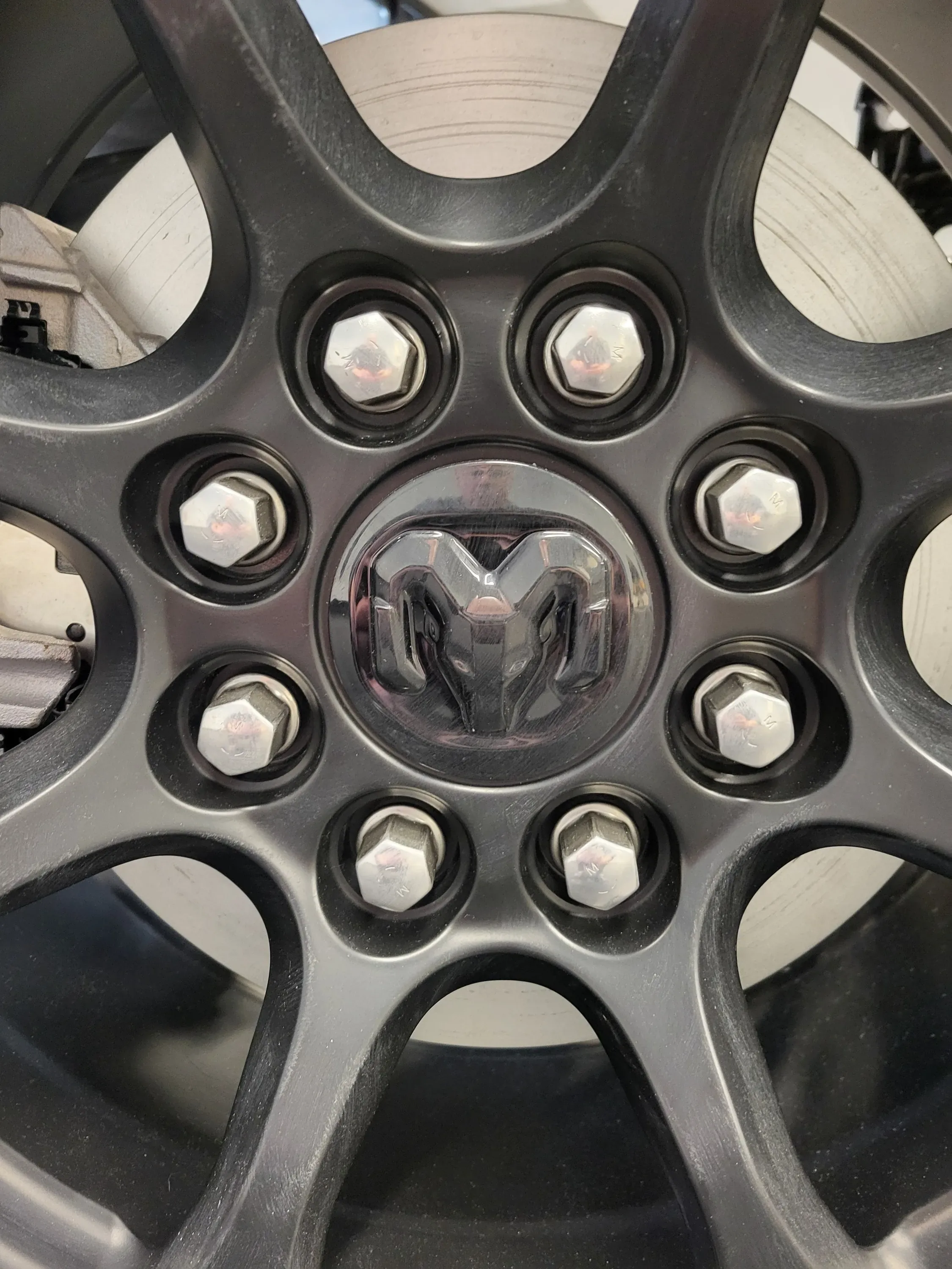 Close-up of a truck wheel's lug nuts and center cap featuring the Ram head logo. Automotive Tire Service Near Kansas City