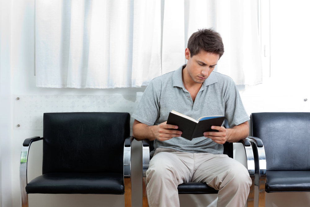 young man reads a book while waiting for Kunes Technicians to finish his car in Kunes Service Center