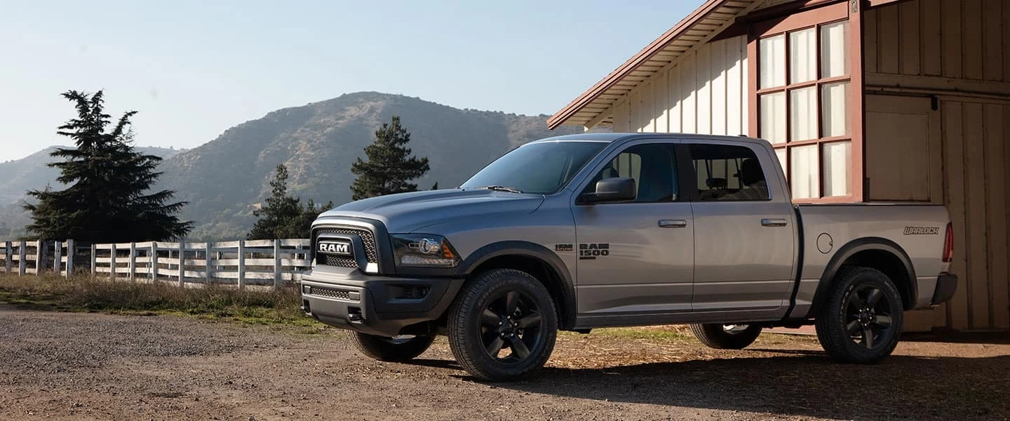 a silver ram truck parked next to a barn