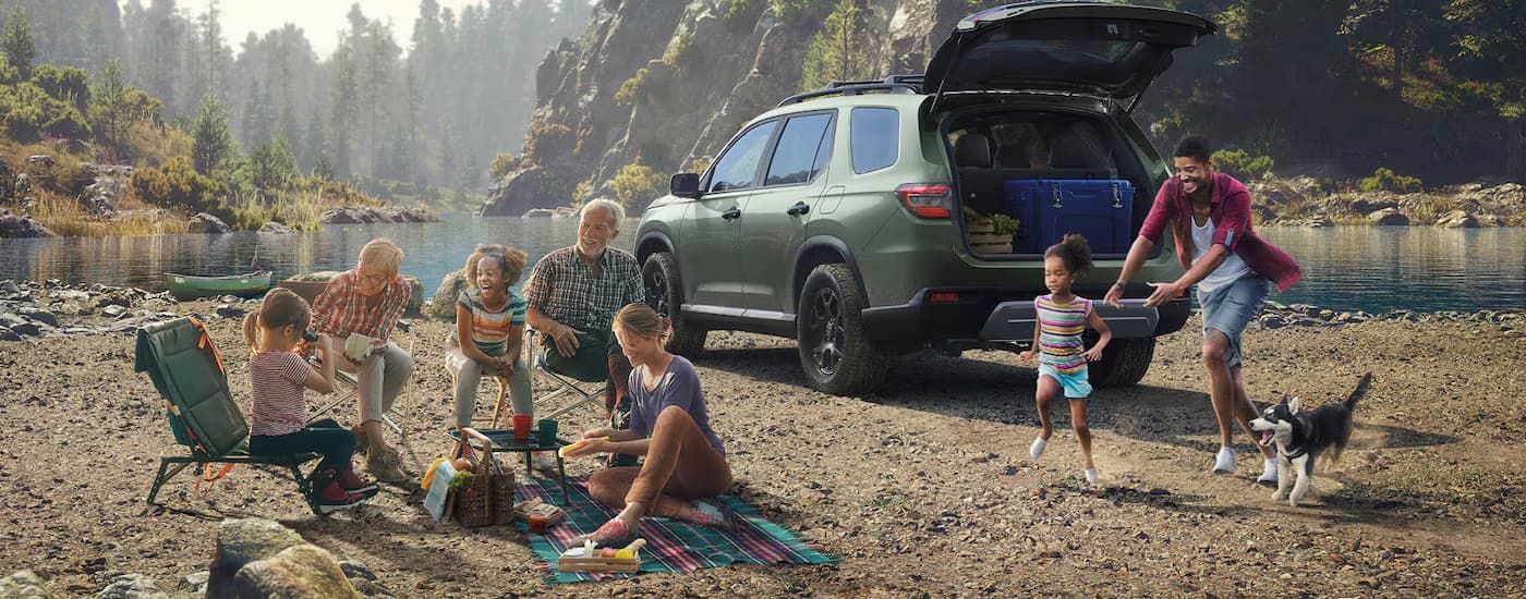 Family next to a green 2026 Honda Pilot by a lake