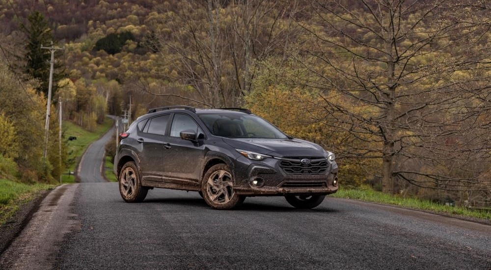 A grey 2024 Subaru Crosstrek Limited is shown parked on a tree-lined road.