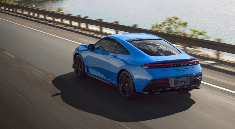 Rear of a blue 2026 Honda Prelude driving down a road.