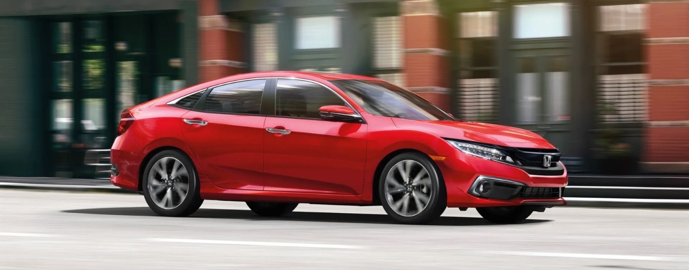 Red 2021 Honda Civic Touring is driving on a city street 